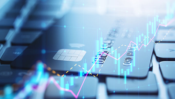 Nahaufnahme einer Kreditkarte auf einer Tastatur, mit Finanzdiagrammen, die Dynamik und Technologie ausstrahlen.