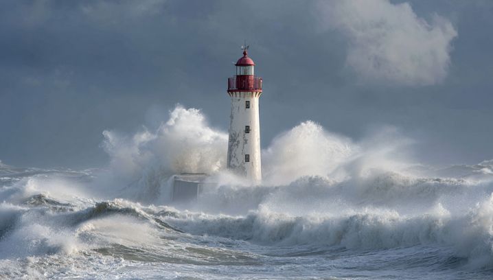 Leuchtturm gegen tobende Wellen, dramatische Wolkenstimmung, vermittelt ein Gefühl von Stärke und Isolation.