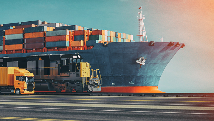 Frachtcontainer auf einem Schiff, neben einem Güterzug und Lkw. Eindruck von industrieller Effizienz.